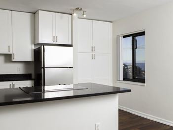 A kitchen with white cabinets and a black countertop at Skye at Belltown Apartments, Seattle, WA